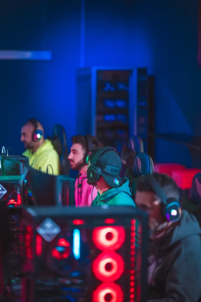Gruppo di amici con cuffie gaming alle postazioni PC della Game Arena di Olbia